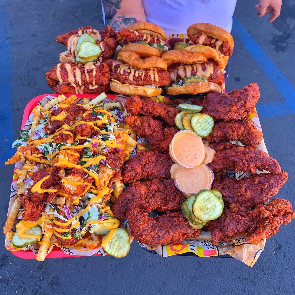 A tray with Dave’s sliders, chicken tenders, loaded fries, pickles and sauces